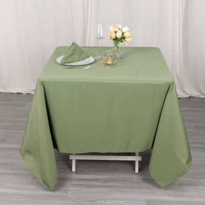 Green tablecloth on a dining table with a floral centerpiece and glassware.
