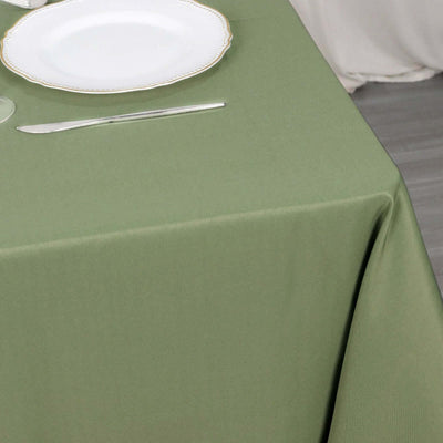 Green tablecloth on a dining table with a plate and cutlery.