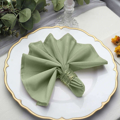 Green fabric napkin elegantly arranged on a decorative plate.