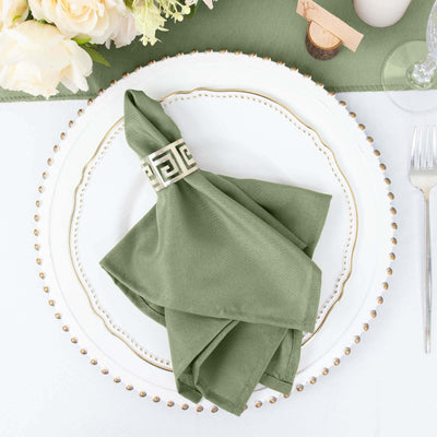 Green napkin with decorative ring on an elegant dinner plate setting.