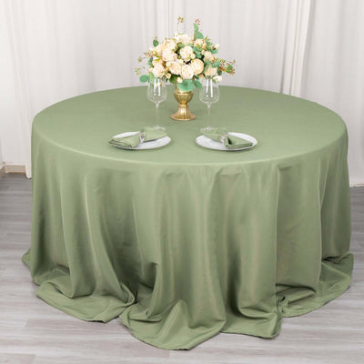 Elegant round table setup with green tablecloth and floral centerpiece.