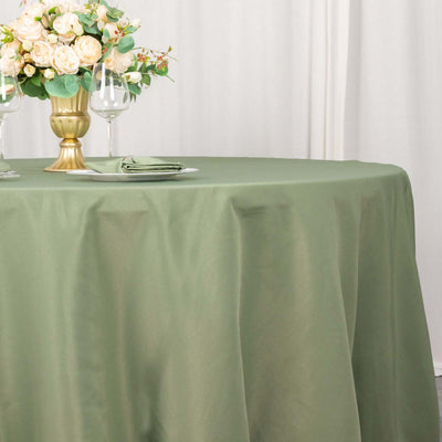 Green tablecloth draped over a table with a vase of flowers and dinnerware.