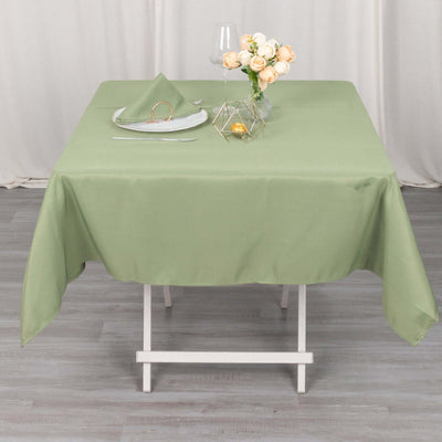 Green tablecloth on a dining table set with a plate and decorative flowers.