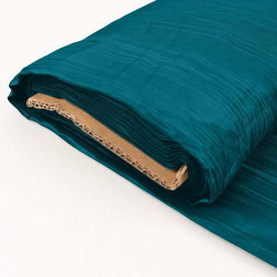 Rolled teal fabric with textured surface on a plain backdrop.