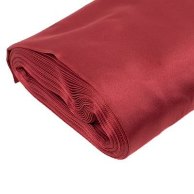 Rolled red satin fabric on a white background