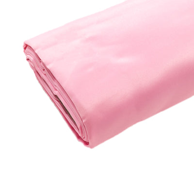 Rolled pink satin fabric on a plain background.