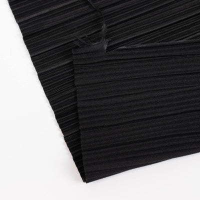 Black pleated fabric close-up with textured ribbed pattern