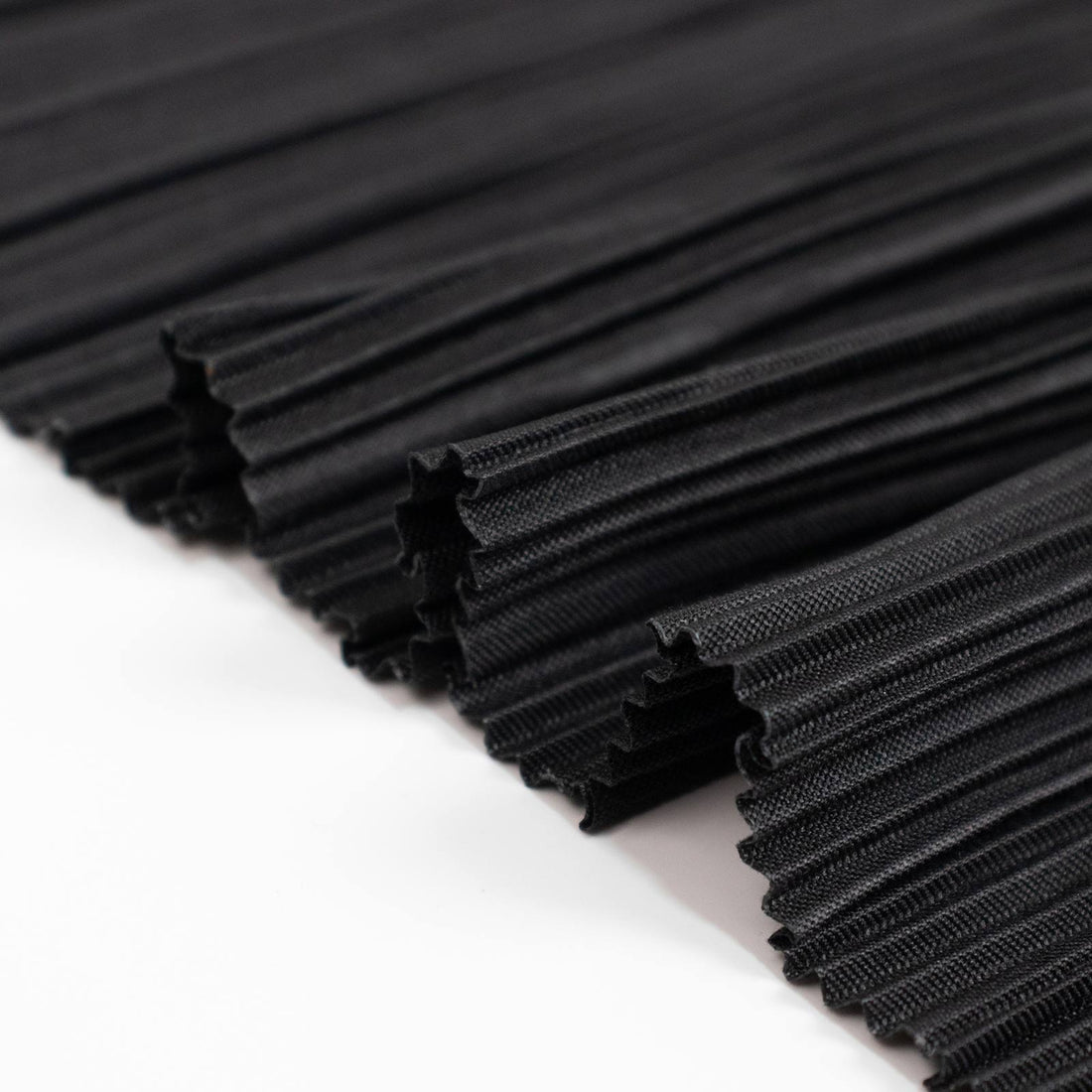 Black corrugated fabric rolls stacked in close-up textured pattern