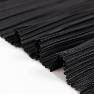 Black corrugated fabric rolls stacked in close-up textured pattern