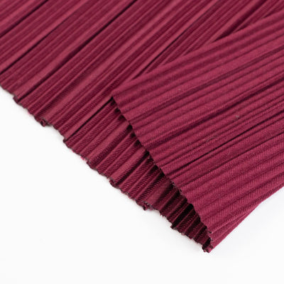 Burgundy pleated fabric close-up on white background