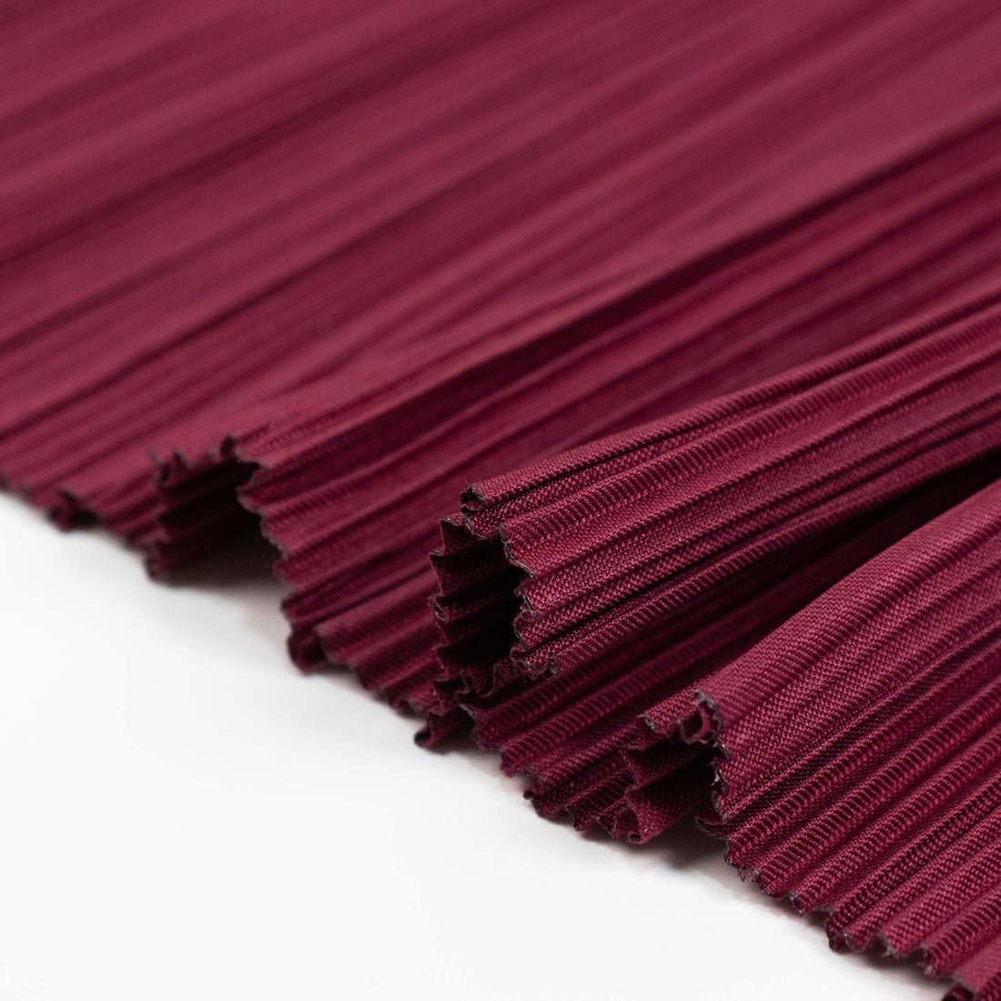 Burgundy pleated fabric close-up texture with folded edges