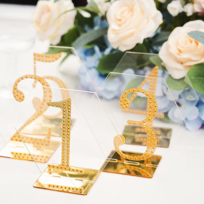 Gold table numbers with rhinestones on a floral table setting.