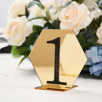 Gold hexagon table number 1 with floral arrangement in the background.