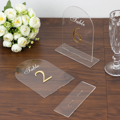 Acrylic table numbers 2 and 6 with gold lettering on a wooden surface.