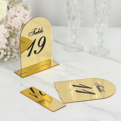 Gold table number holder with "Table 19" design on a marble surface.