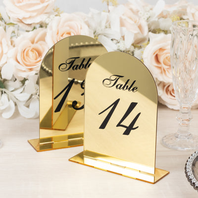 Gold table number signs with floral decor in the background.