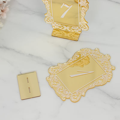 Gold table number 7 with ornate frame design and matching holder on marble background.
