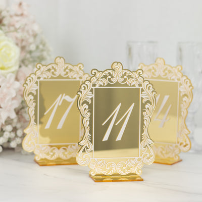 Elegant gold table numbers in ornate frames for wedding decor.