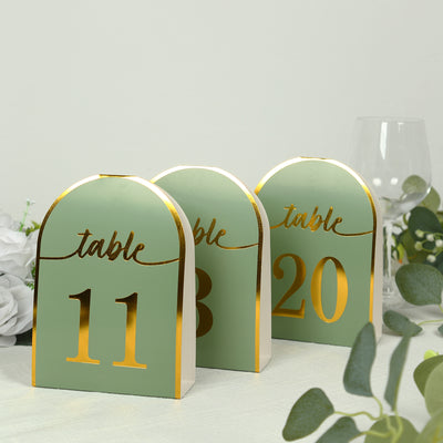 Elegant table number stands in green and gold for event decor.