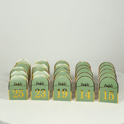 Table numbers in green and gold, arranged in a row for event decoration.
