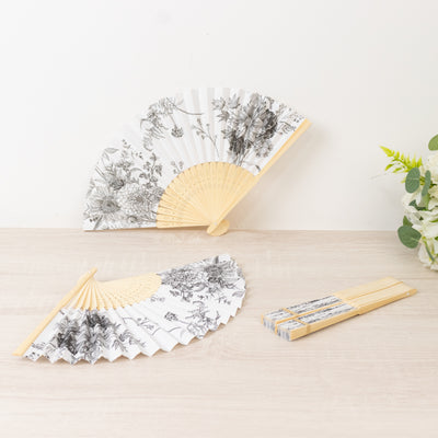 Elegant floral patterned folding fans on a light wooden surface.