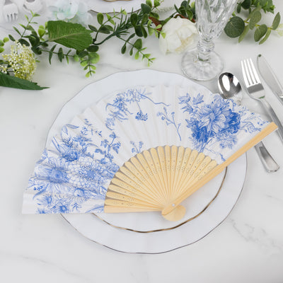 Blue floral decorative fan on a dining plate setting.