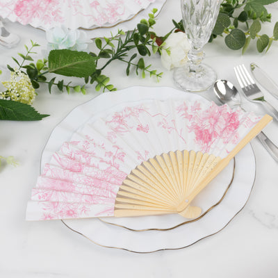 Decorative pink floral fan on a dining table setting with elegant tableware.