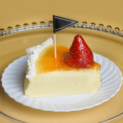 Slice of cheesecake topped with strawberry and orange glaze on a decorative plate.
