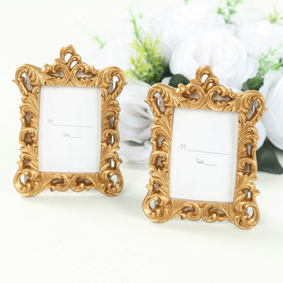 Ornate gold picture frames with blank inserts against a floral backdrop.