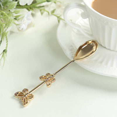 Gold butterfly spoon beside a cup of tea on a saucer.