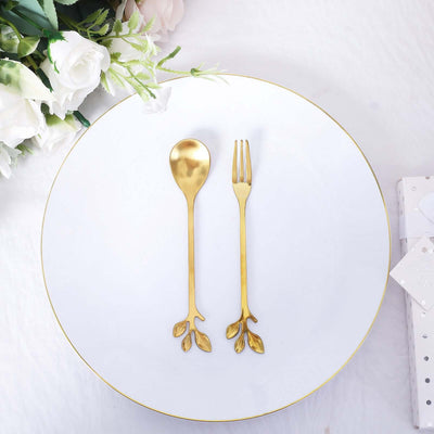 Gold leaf design spoon and fork on a white plate with floral accents.