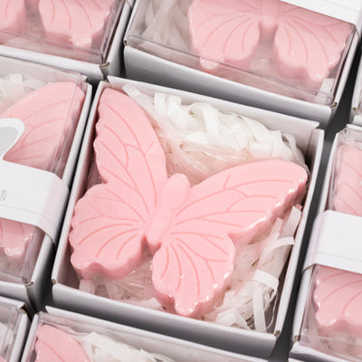 Pink butterfly-shaped soap in white box with shredded paper.