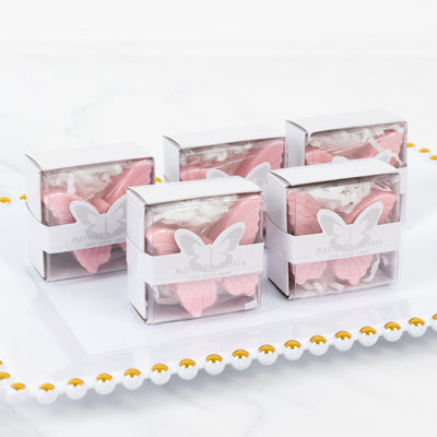 Pink butterfly-shaped soaps in clear boxes on a white plate.