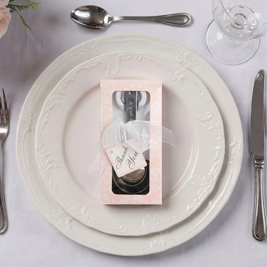 Elegant favor box with cutlery on a decorative plate setting.