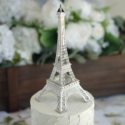Silver Eiffel Tower cake topper on a white frosted cake.