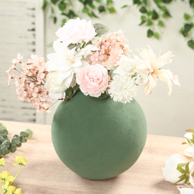 Green vase with assorted pastel artificial flowers.