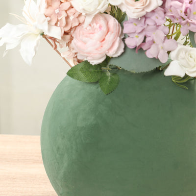 Green ceramic vase with pink and white floral arrangement.