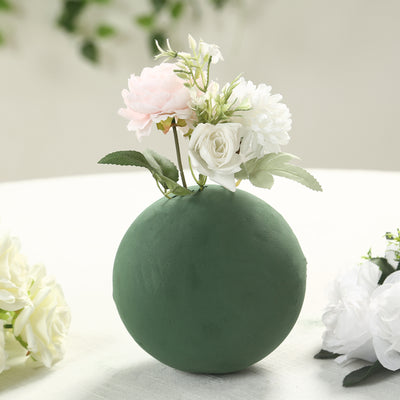 Green spherical vase with artificial flowers arrangement.