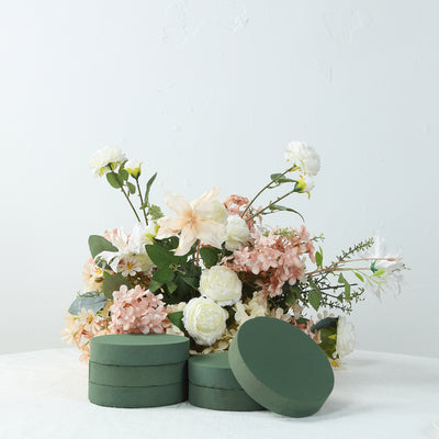 Green floral foam discs stacked in front of a floral arrangement.
