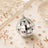 Silver disco ball ornament on beige background with rose gold confetti