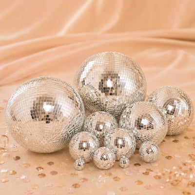 Silver disco balls on a peach background with confetti, party decor close-up
