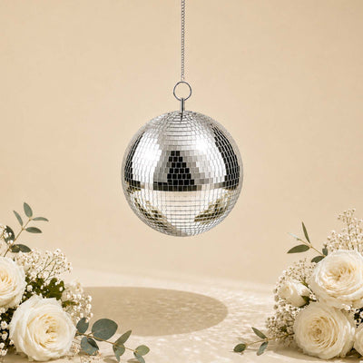 Hanging silver disco ball with white roses and greenery on beige background