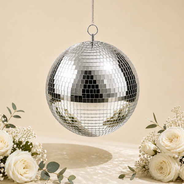 Silver mirrored disco ball hanging with white roses on a soft beige background