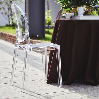 Transparent acrylic chair beside a table in an outdoor setting.