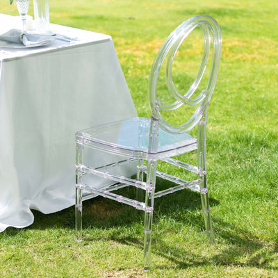 Clear acrylic chair beside a table on a grassy outdoor setting.