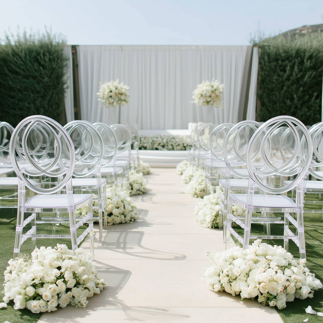 Elegant outdoor wedding setup with clear chairs and floral arrangements.