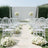 Elegant outdoor wedding setup with clear chairs and floral arrangements.