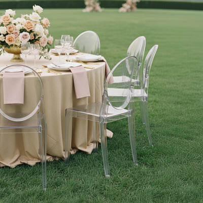 Elegant outdoor dining setup with a floral centerpiece and ghost chairs.