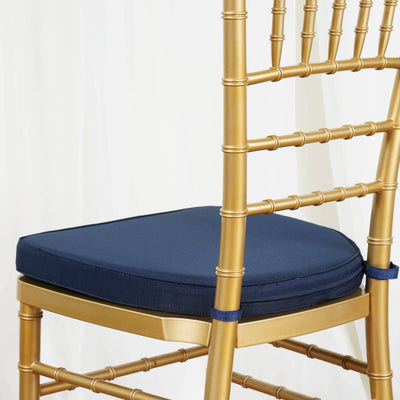 Gold chiavari chair with navy cushion on a plain background.