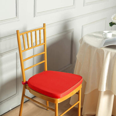 Red chair cushion on a wooden chair beside a table with a magazine.